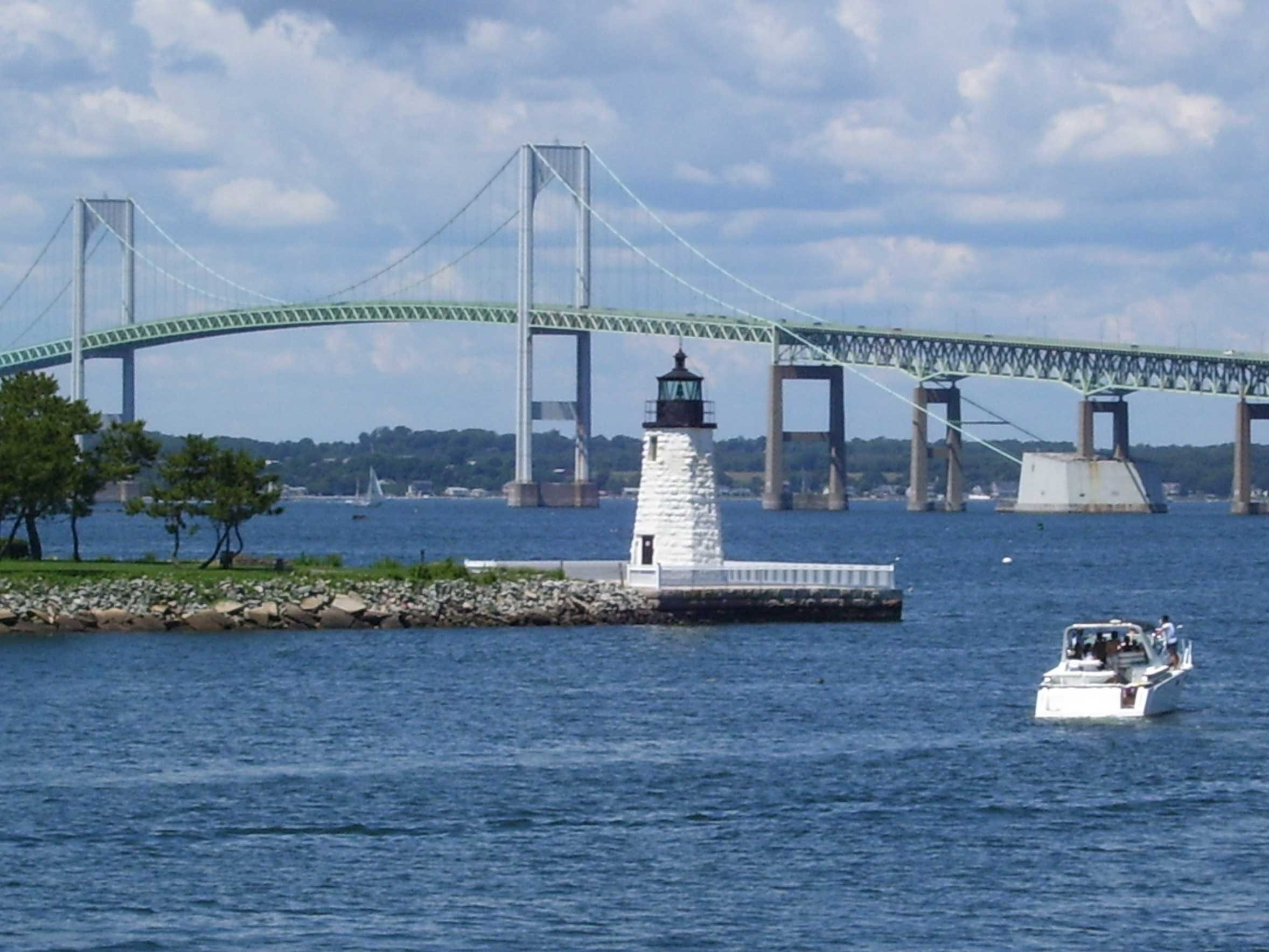 Photograph of the Newport harbor with a lighthouse and Newport bridge in the background